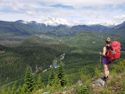 Kristine of Hikes Near Vancouver portant un sac à dos Vaude de 60 litres au bord d'une falaise surplombant une vallée en Colombie-Britannique.