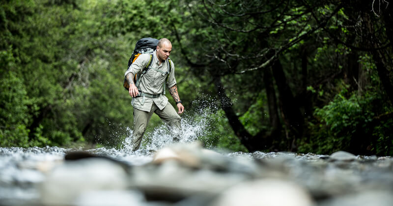 Keven Martel crossing a river while on a expedition