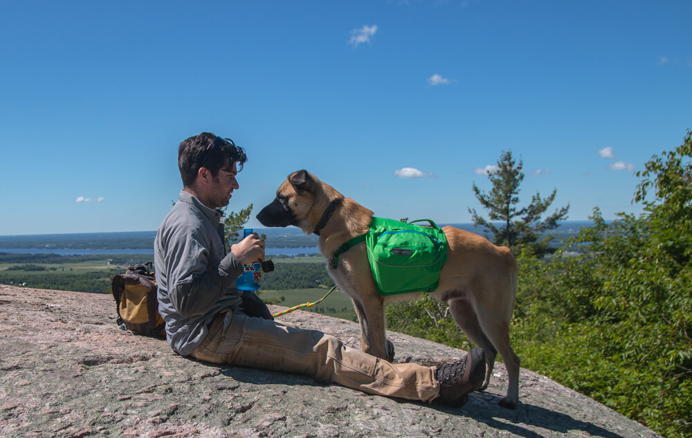 Dean Campbell taking a break and drinking water with his dog during a hike